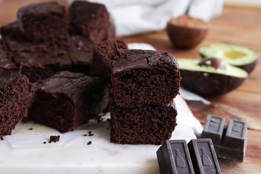 Keto Avocado Brownies on a table with chocolate and a cut avocado