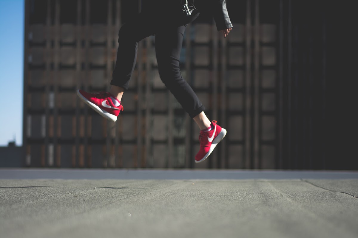 Woman in red sneakers jumping with her feet off the ground