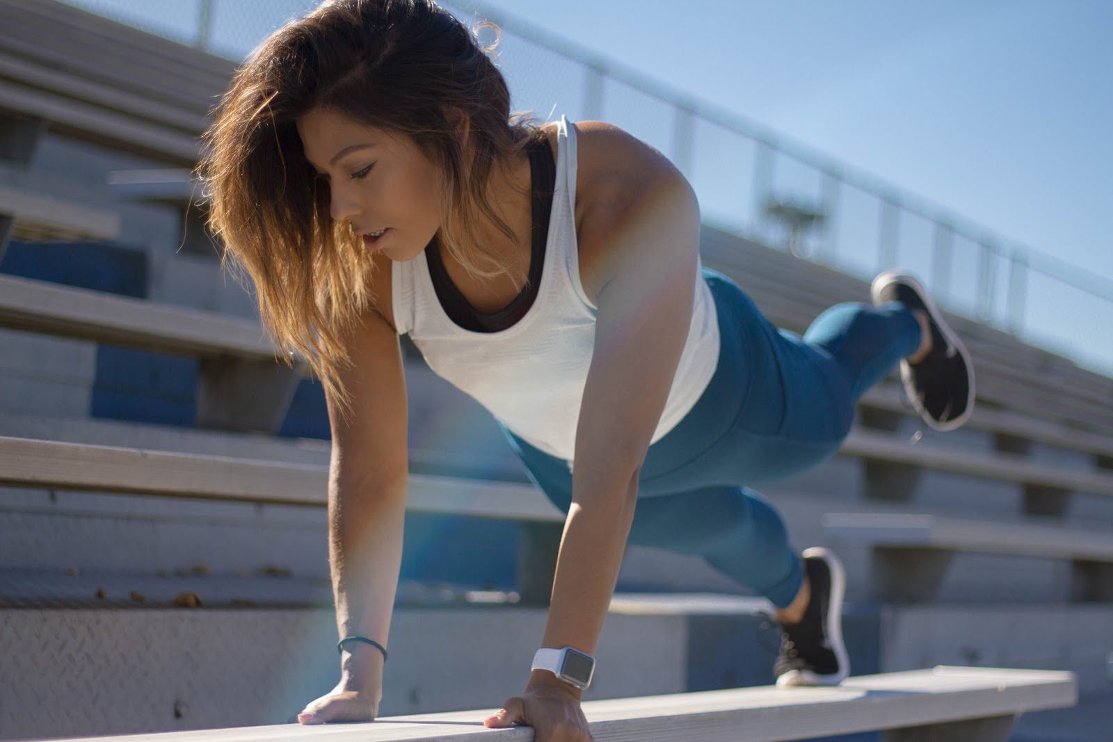 Woman on a stadium bench doing plyometric exercises